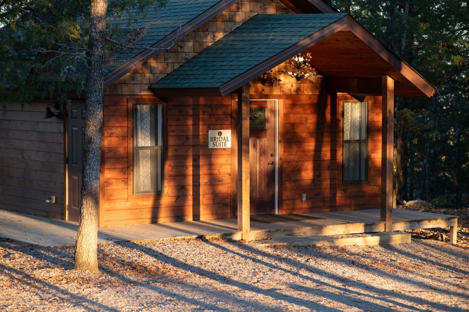 A cabin with a porch and trees in the background.
