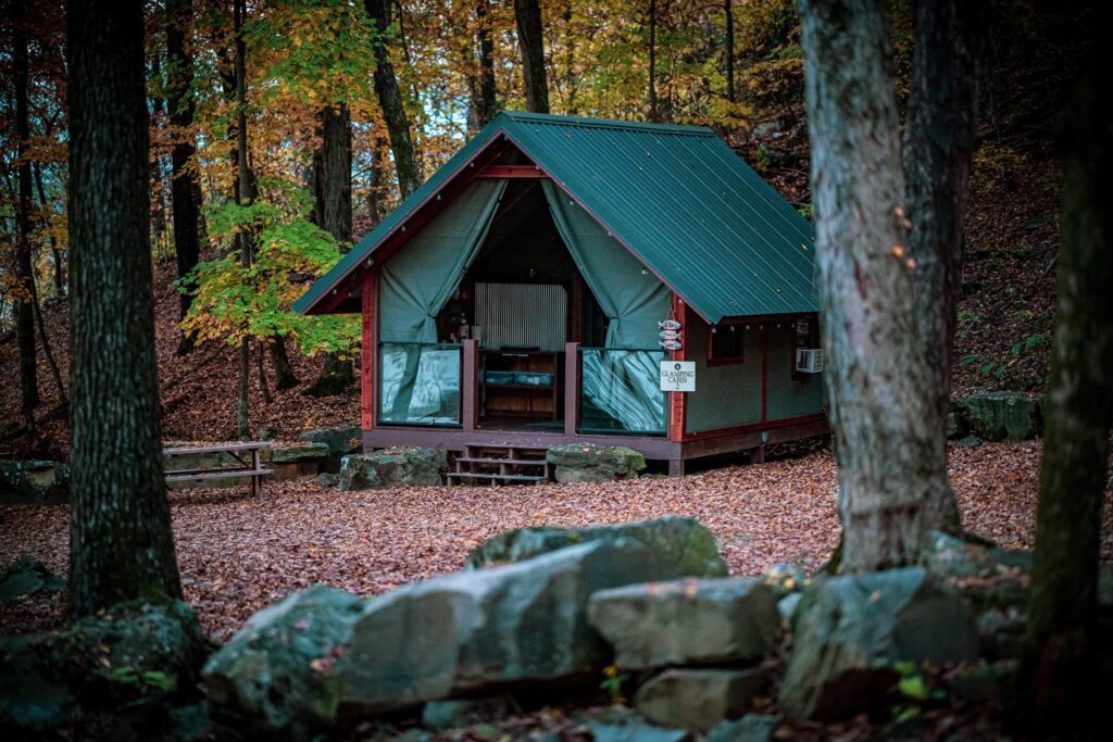A green tent in the woods with rocks and trees.