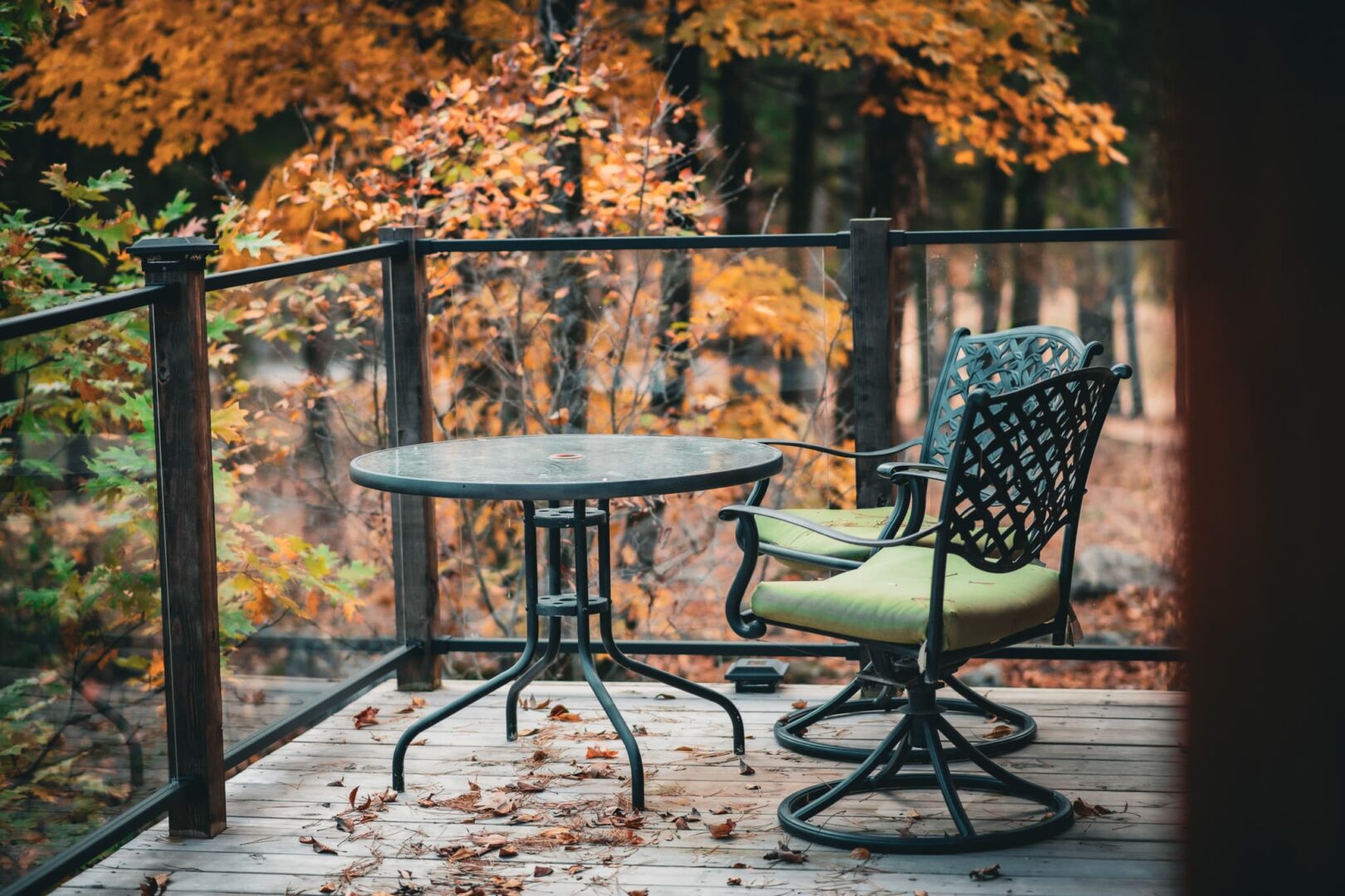 A table and chair on the deck of an outdoor patio.