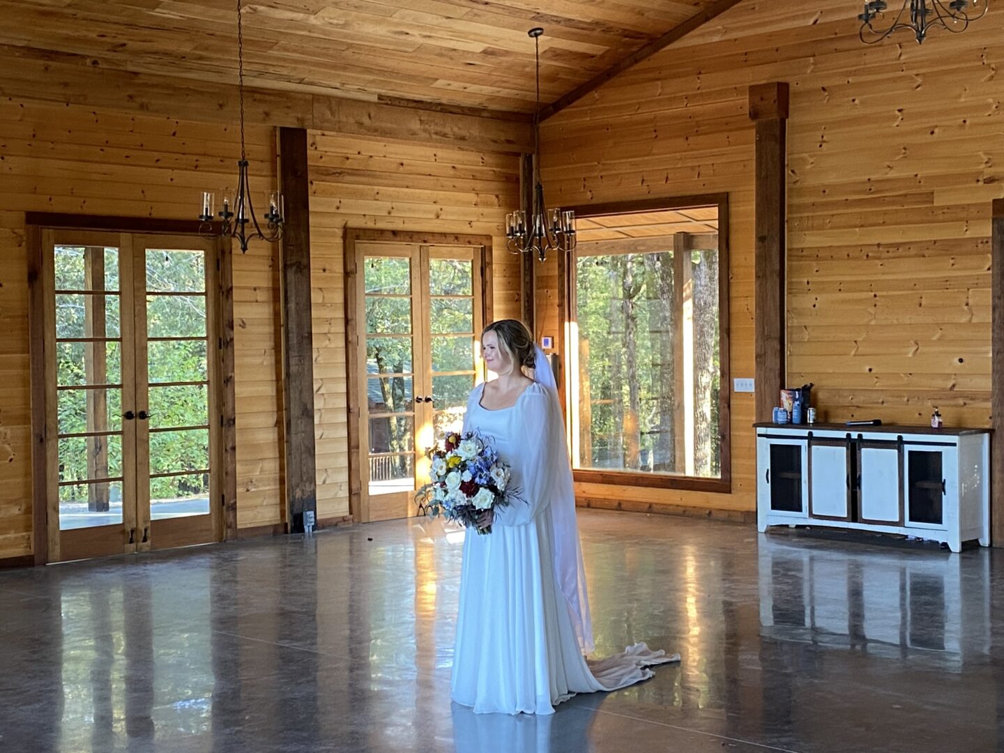A bride in her wedding dress standing inside of a room.