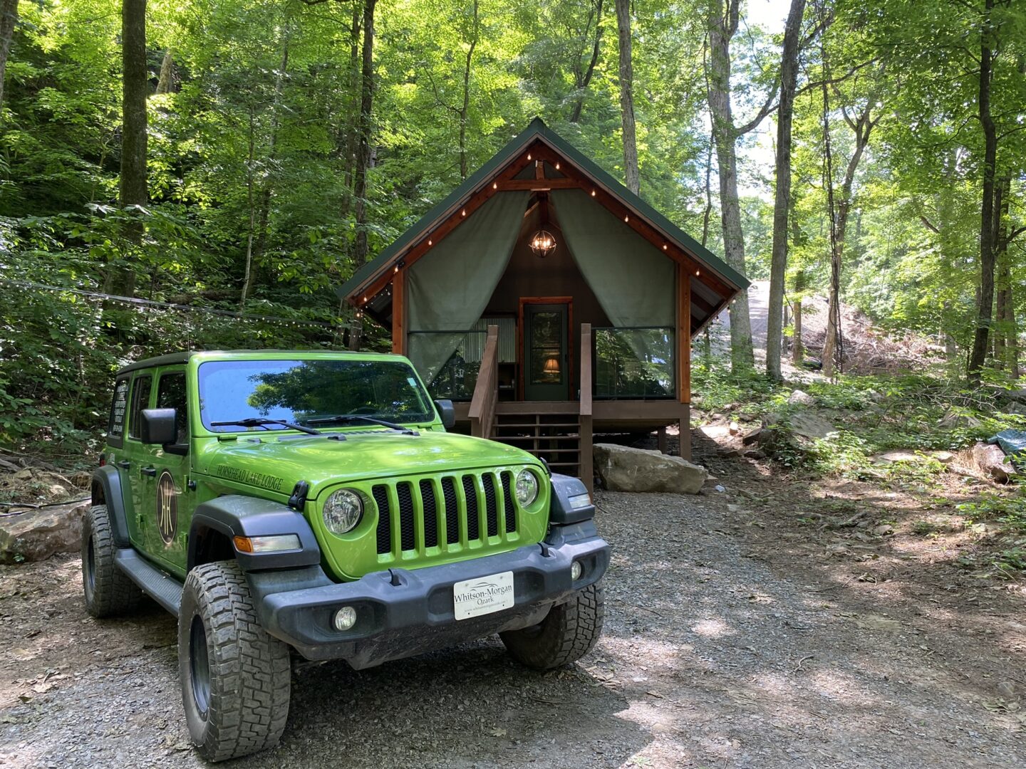 A green jeep parked in front of a tent.