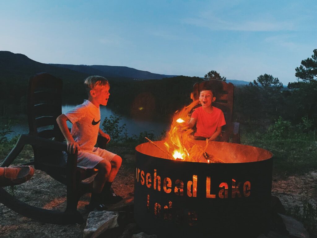 Two people sitting in front of a fire pit.